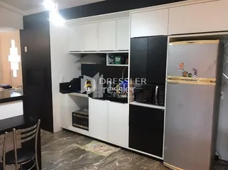 Cozinha com armários brancos e geladeira preta em um imóvel.