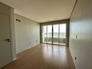 Interior de uma sala com piso de madeira e portas de vidro que dão para o exterior.