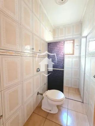 Foto interna de um banheiro com revestimento branco.