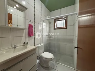 Banheiro com box de vidro e revestimento branco.