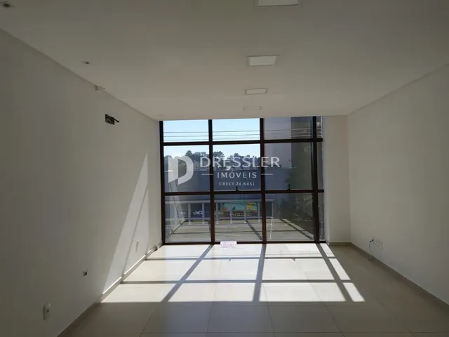 Vista interna de um ambiente com grandes janelas de vidro.