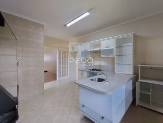 Vista da cozinha com armários brancos e bancada de granito.