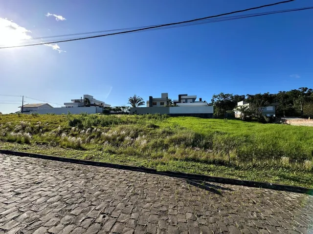 Vista externa de uma área gramada e pavimento de paralelepípedos sob um céu azul claro.