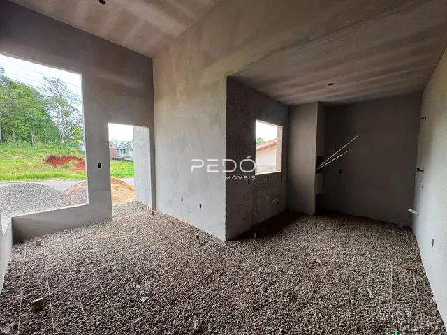 Vista interna de um espaço com paredes de concreto aparente e piso de brita.
