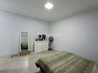 Quarto com cama e cômoda em um ambiente claro.