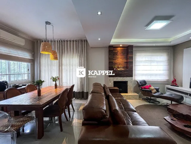 Sala de estar com sofá de couro marrom e mesa de jantar de madeira em um apartamento em Lajeado.