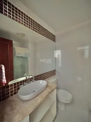 Foto de um banheiro com bancada e azulejos marrons.