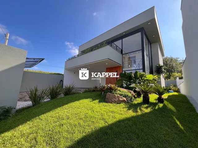 Fachada de uma casa moderna branca com jardim verde bem cuidado.