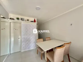 Uma sala de jantar com mesa branca e cadeiras claras.