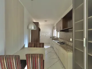 Interior de uma sala de jantar conectada à cozinha em um imóvel no Brasil.