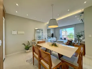 Sala de jantar e estar com mesa de madeira clara.