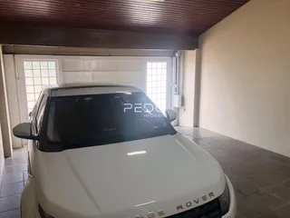 Imagem da entrada de uma propriedade com um carro estacionado no interior.
