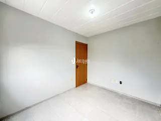 Hall de entrada com piso de cerâmica e porta de madeira.