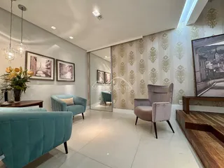 Sala de estar com sofá azul e poltronas em um ambiente decorado com papel de parede.