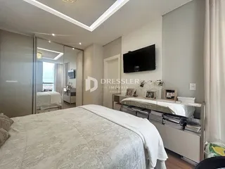 Quarto com cama e televisão instalada na parede.