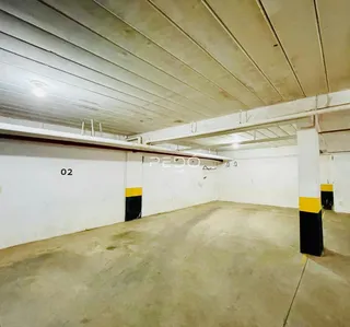 Interior de um ambiente com teto e paredes brancas e piso de concreto aparente.