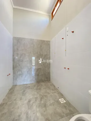 Interior de um banheiro com revestimento de azulejos cinzas e brancos.