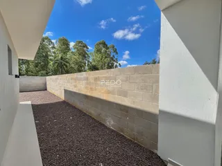 Parede externa de alvenaria com área de terra batida no quintal.