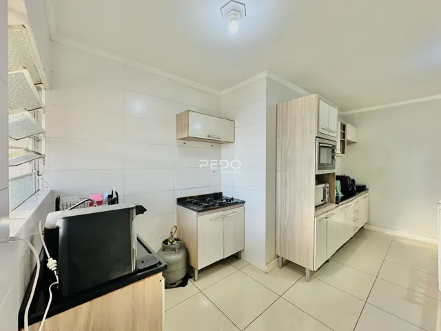 Foto de uma cozinha moderna com armários brancos e piso claro.