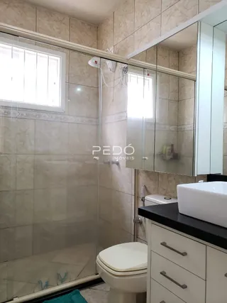 Foto de um banheiro com revestimento cerâmico e box de vidro.
