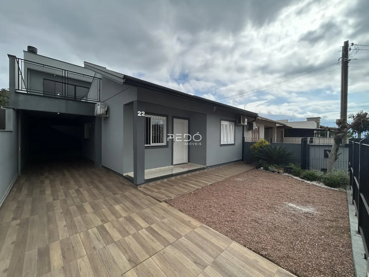 Fachada de uma casa moderna em Lajeado, Brasil, com área coberta e piso de madeira.