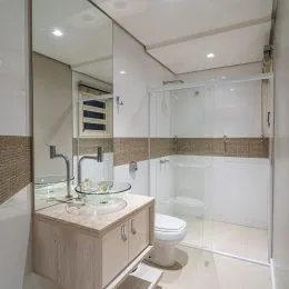 Foto de um banheiro com box de vidro e revestimento cerâmico.