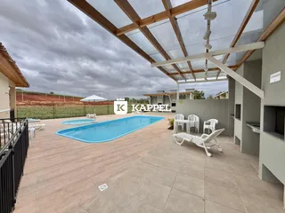 Vista externa da piscina com deck e área coberta em uma propriedade.