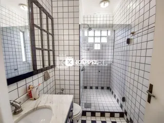 Banheiro com revestimento de azulejos brancos e bancada de mármore.