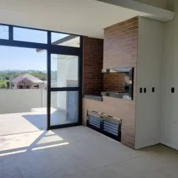Vista da área externa com parede de tijolos e grandes portas de vidro.
