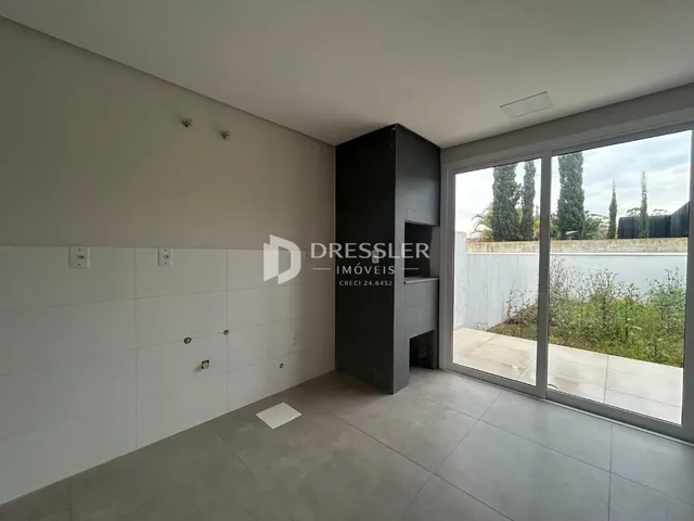 Interior de uma sala com paredes brancas e piso cinza claro.