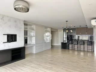 Interior de uma cozinha moderna com armários brancos e piso de madeira clara.