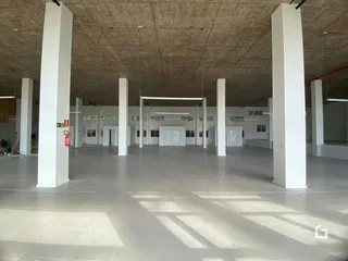 Interior de um grande espaço com colunas brancas e teto de concreto.