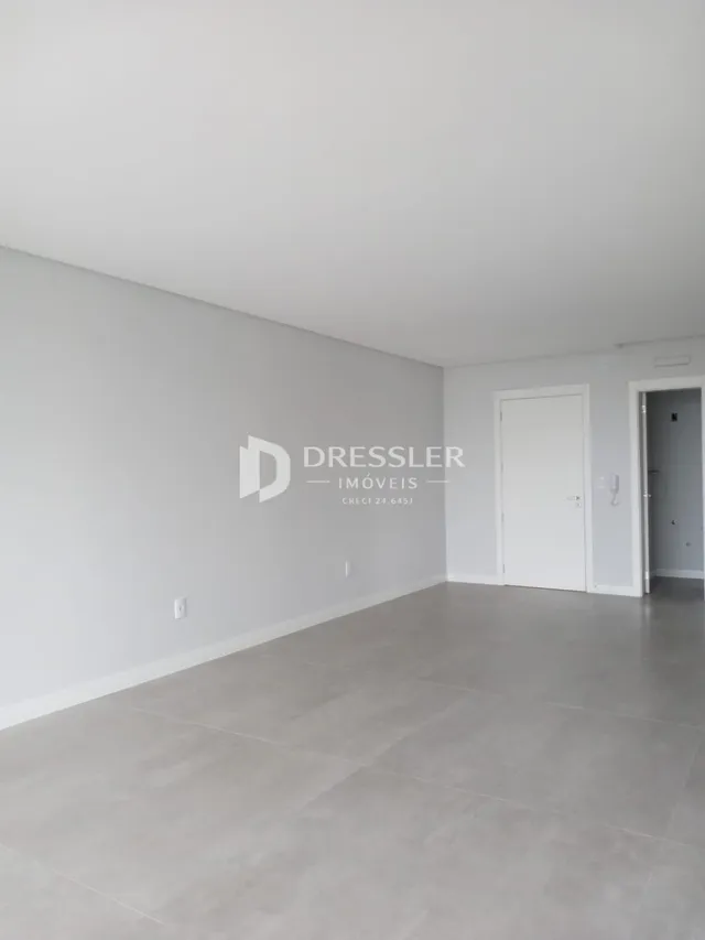 Ambiente interno de uma sala com paredes brancas e piso cinza claro.