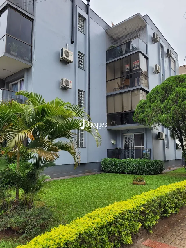 Fachada de um prédio residencial em Lajeado, Brasil, com jardim verde na frente.
