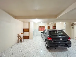 Hall de entrada com piso de cerâmica e um carro estacionado.