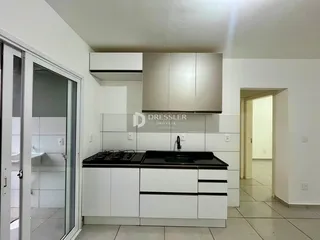 Cozinha moderna com armários brancos e bancadas escuras.