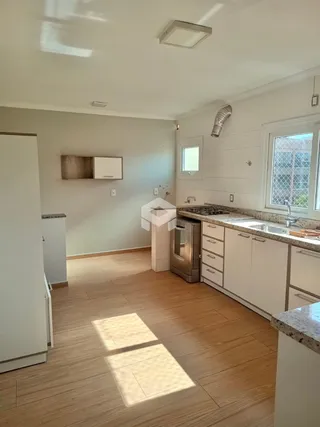 A cozinha com piso de madeira e armários brancos é visível na foto.