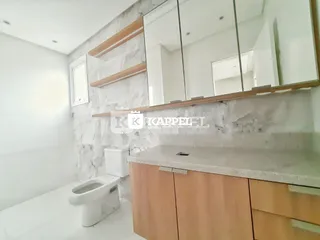 Foto de um banheiro com bancada de madeira e vaso sanitário branco.