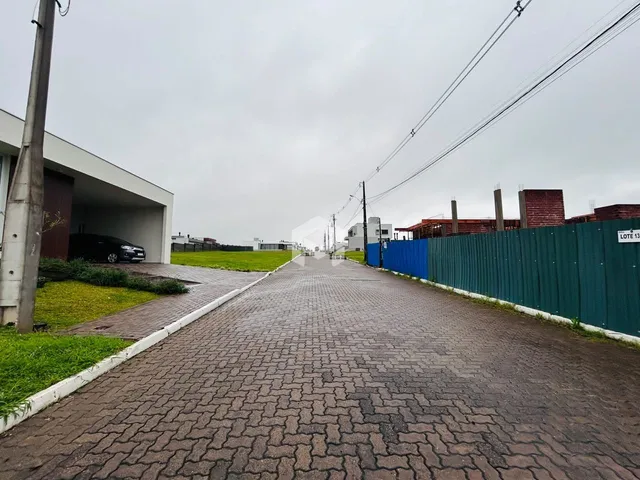 Vista externa de uma propriedade com muro e área gramada.
