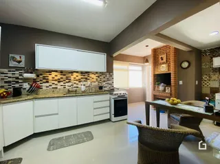 Sala de estar com cozinha integrada e lareira em um imóvel no Brasil.