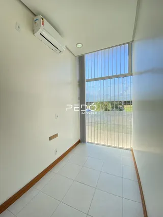 Corredor interno com piso de cerâmica e janela grande.
