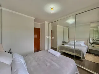 Quarto com cama e espelho refletindo o ambiente.