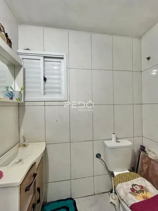 Foto de um ambiente interno com revestimento de azulejos brancos e um vaso sanitário.