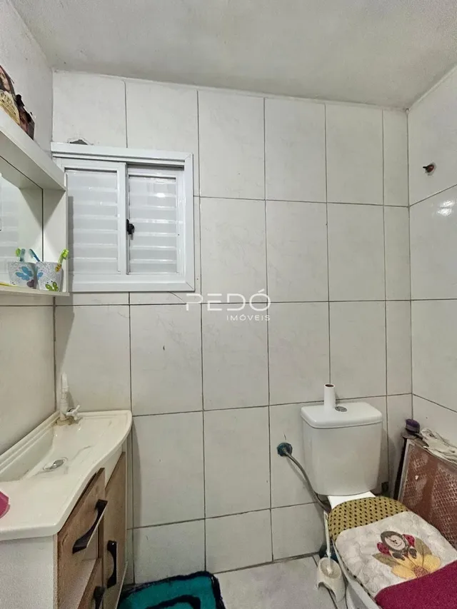Foto de um ambiente interno com revestimento de azulejos brancos e um vaso sanitário.