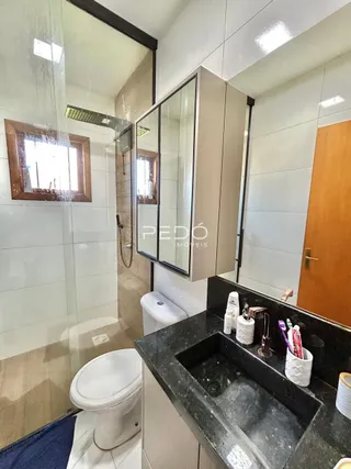 Foto de um banheiro interno com box de vidro e louças sanitárias.