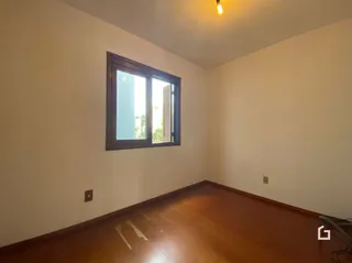 Quarto interno com piso de madeira e janela.