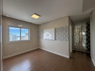 Sala de estar com piso de madeira e janela com vista da cidade.