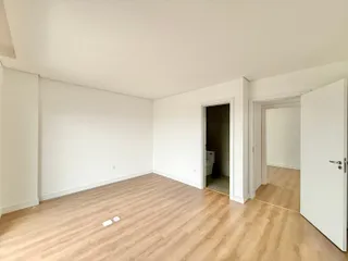 Sala ampla com piso de madeira clara e paredes brancas.