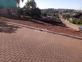 Vista da propriedade com calçada e declive de terra no fundo.