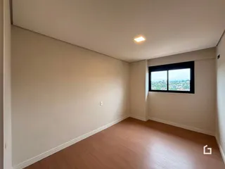 Ambiente interno de uma sala com piso de madeira e vista para a paisagem.